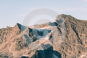 Sunset light over retiring dying glaciers on the Italian French Alps. Climate change concept. Toned desaturated image.