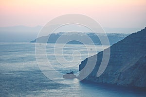 Sunset light with purple and red over the ocean with blurred view on Oia at Fira, Santorini, Greece