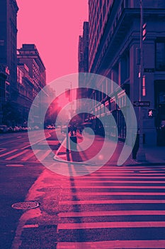 Sunset light shines on an empty crosswalk at the intersection of 23rd Street and 5th Avenue in New York City in pink and blue
