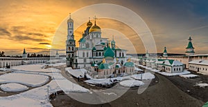 Sunset lights over Voskresensky cathedral golden domes, covered in snow, Resurrection or New Jerusalem Monastery, Istra, Moscow