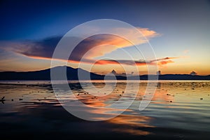 Sunset lights up a large cloud over a mountain top reflecting on Lake Chapala in Ajijic Mexico