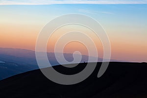 Before sunset, a lone horse stands on the top of the mountain