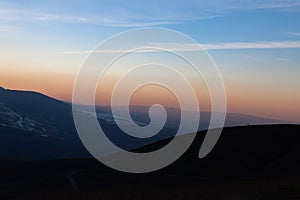 Before sunset, a lone horse stands on the top of the mountain