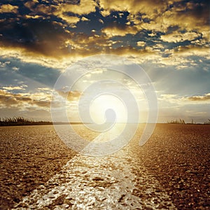 Sunset in low clouds over asphalt road with white line