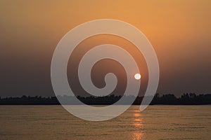 Sunset low sun in orange sky at river Assam in India