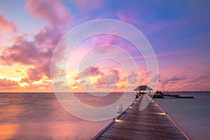 Sunset on Maldives island, luxury water villas resort and wooden pier. Beautiful sky and clouds