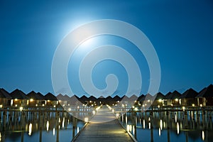 Sunset on Maldives island, luxury water villas resort and wooden pier. Beautiful sky and clouds and beach background