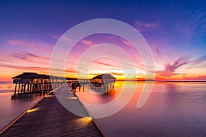 Sunset on Maldives island, luxury water villas resort and wooden pier. Beautiful sky and clouds and beach background for summer va
