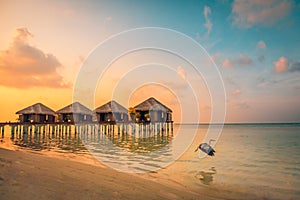 Sunset on Maldives island, luxury water villas resort and wooden pier. Beautiful sky and clouds and beach vacation for summer