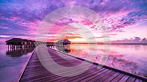 Sunset on Maldives island, luxury water villas resort and wooden pier. Beautiful sky and clouds and luxury beach background