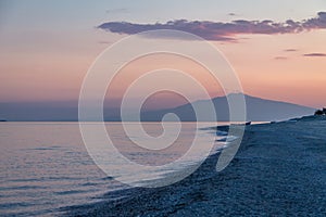 Sunset on a Mediterranean beach of Ionian Sea with Mount Etna Volcano on background - Bova Marina, Calabria, Italy