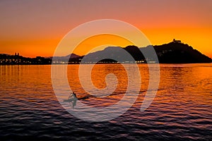 Sunset on Mount Igueldo and and man with a paddle in koyak in Donosti San Sebastian, Basque Country, northern spain photo