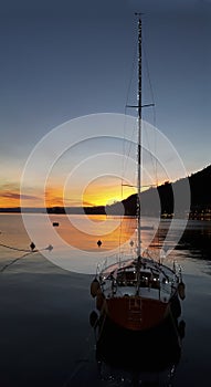 Sunset with mountain, lake and sail boat