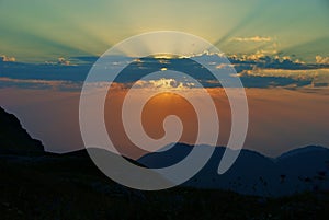 Sunset in the mountains. Beautiful view of the setting sun, mountains and clouds.