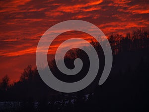 Sunset in the mountains with orange red sky and clouds. Winter Carpathian Mountains Ukraine, Europe. Cloudscape view .