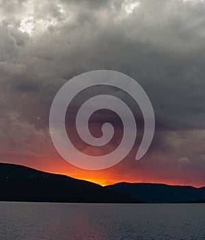 Sunset in the Mountains, Sun Disk Sets Below the Horizon, Sky is Covered with Gray Sheetlike Clouds. Background. Copy