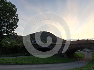 Sunset Nature Bridge Landscape. Trees and Grass in Germany. Multiple Colours in the sky. Blue Purple Pink. Also a small lake