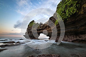 Sunset near famous tourist landmark of Bali island - Tanah Lot & Batu Bolong temple.