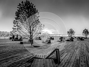 Sunset on the Neva river wooden embankment with benches in Saint-Petersburg overlooking the bridge across the bay