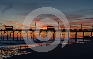 Colorful Sunset at ocean coast with silhouette of pier and photo