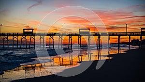 Colorful Sunset at ocean coast with silhouette of pier and photo