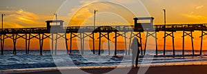 Colorful Sunset at ocean coast with silhouette of pier and photo