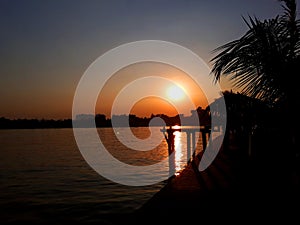 Sunset observable through coconut trees and the reflection of sun is visible in the water lake at Eco Park Kolkata India photo