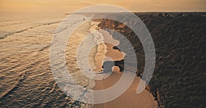 Sunset ocean seascape with waves at rock wall on sand beach aerial view. Nobody nature scenery