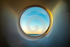 Sunset ocean view of horizon seen from inside of a cruise ship cabin through a round circular window