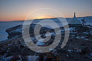 Sunset on Ogoy island on Lake Baikal overlooking a Buddhist stupa, a frozen lake and mountains behind it.