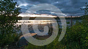 Sunset with old dock and old row boat on small remote lake in Northern Wisconsin - clouds and weather coming in