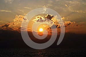 Sunset in the open ocean. Colorful views of the surface of the water and the sky with clouds over ocean.