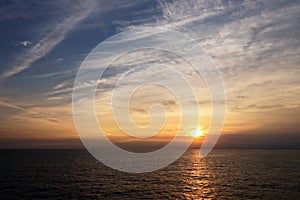 Sunset in the open ocean. Colorful views of the surface of the water and the sky with clouds over ocean.