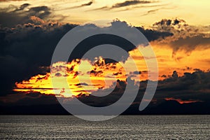 Sunset in the open ocean. Colorful views of the surface of the water and the sky with clouds over ocean.