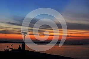 Sunset with orange and blue sky with bicycle and man