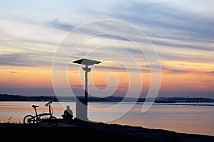 Sunset with orange and blue sky with bicycle and man