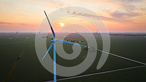 Sunset of orange and pink with wind turbines in green fields aerial