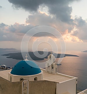 Sunset over aegean sea with view to Virgin Mary Catholic Church Three Bells of Fira, Santorini.