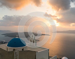 Sunset over aegean sea with view to Virgin Mary Catholic Church Three Bells of Fira, Santorini.