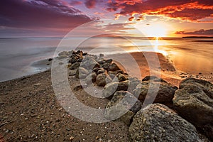 Sunset over a beach with large rocks