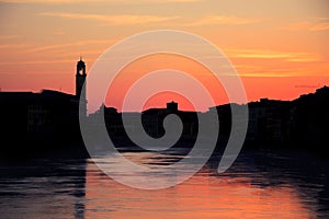 Sunset over black silhouette of Pisa cityline and Aron river photo