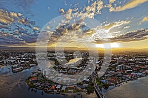 Sunset over city at river by scattered clouds aerial view