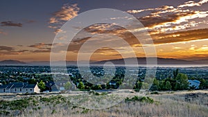 Sunset over a city in a valley with mountains and a large lake in the distance