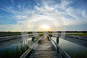 Sunset over coastal waters with a very long wooden boardwalk