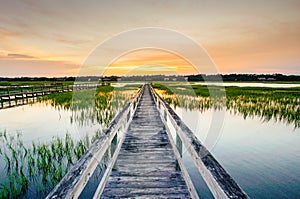 Sunset over coastal waters with a very long wooden boardwalk