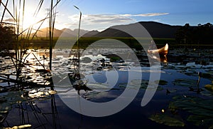Sunset over dam with canoe in background, Garden Route, South Africa