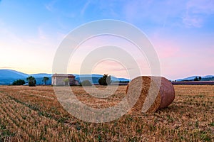 Sunset over farm field with hay bales near Sault