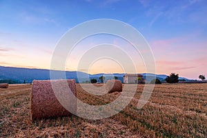 Sunset over farm field with hay bales near Sault