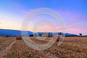 Sunset over farm field with hay bales near Sault