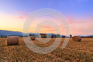 Sunset over farm field with hay bales near Sault